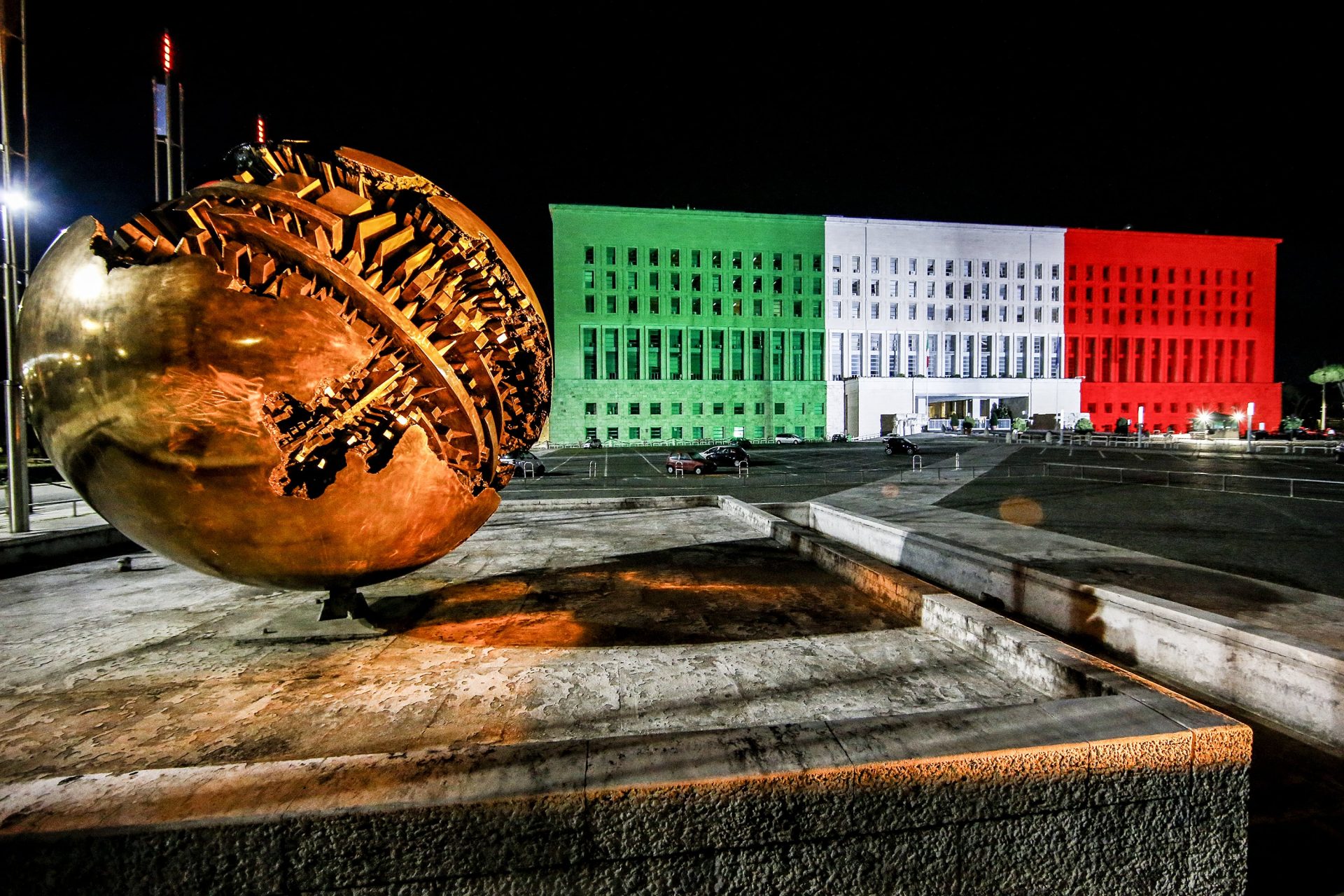 La Sfera di Pomodoro davanti al Palazzo della Farnesina illuminato con il tricolore
